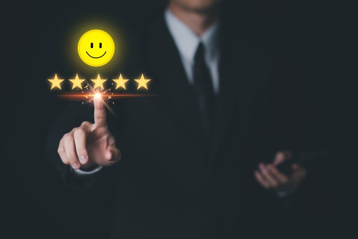 Businessman selecting a smiling face and a five star rating, signifying employee satisfaction 